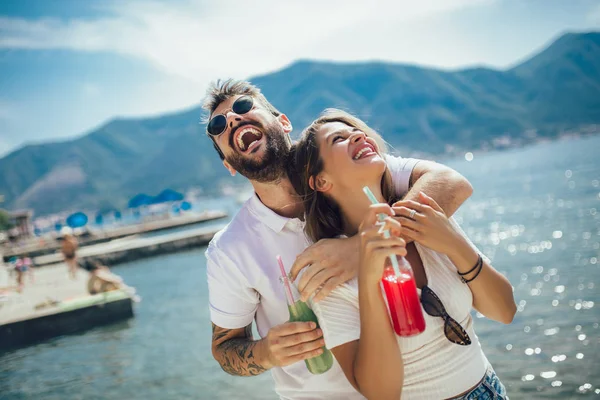 Pareja joven comiendo fruta en la playa- fiesta de verano con un amigo —  Fotos de Stock