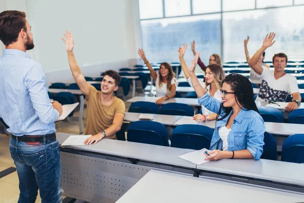 Grupa studentów podnosząc ręce w klasie na wykład — Zdjęcie stockowe