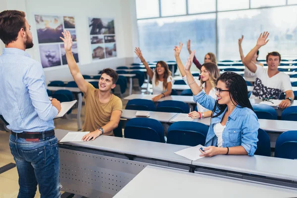 Groep studenten verhogen handen in de klas op Hoorcollege — Stockfoto