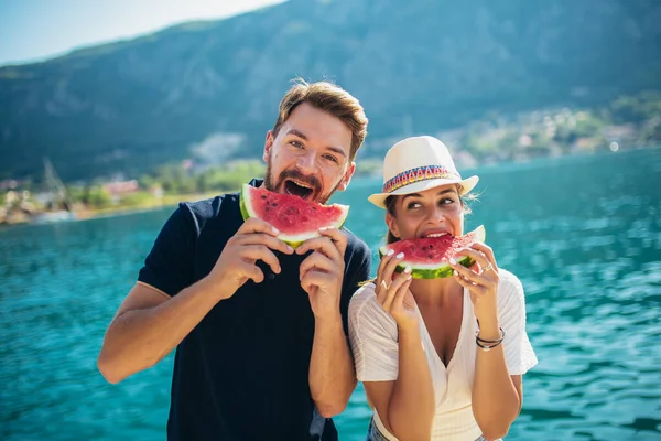 若い笑顔のカップルが楽しいビーチでスイカを食べる — ストック写真