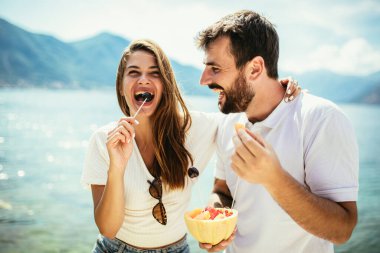 Genç mutlu çift sahilde meyvelerle eğleniyor.