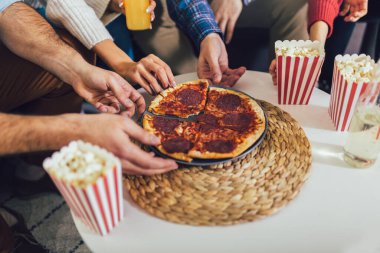 Pizza ve patlamış mısır yiyen meslektaş ya da arkadaşların elleri. Evde parti veriyorlar, pizza yiyorlar ve eğleniyorlar..
