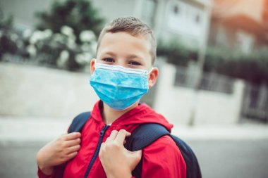 Çocuk koronavirüs ve grip salgını sırasında yüz maskesi takıyor. Çocuk okula gitmeden önce maske takıyor. Salgını önlüyor. Havada bulaşıcı hastalık ve toz var..