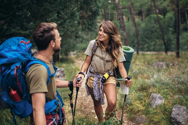 Backpackers couple hiking during fall with sticks