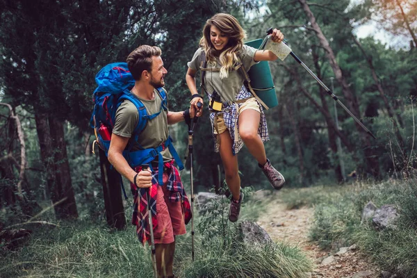 Backpackers couple hiking during fall with sticks