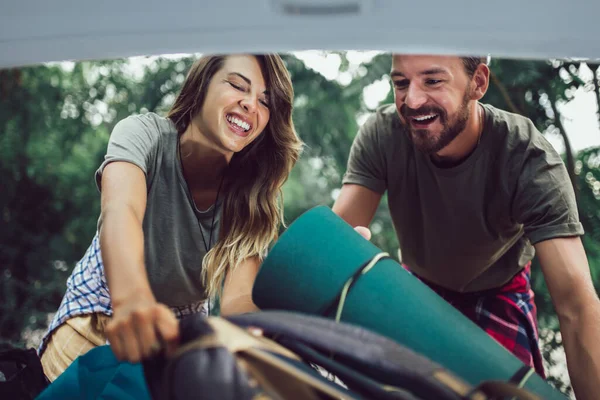 Genç çift kamp malzemelerini yerleştirirken eğleniyor.