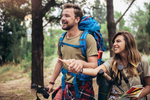 Backpackers couple hiking during fall with sticks