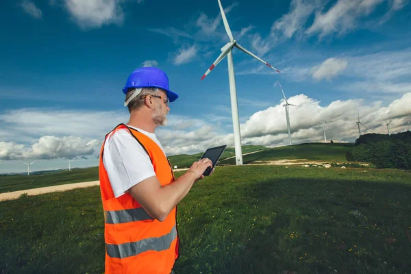 stock image Windmill engineer inspection and progress check wind turbine, using digital tablet.