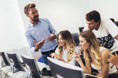 Üniversite öğrencileri sınıfta oturup, ders sırasında bilgisayar kullanıyorlar..