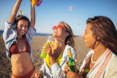 Üç arkadaş sahilde yürüyor ve bir yaz günü gülüyor, tatilin tadını çıkarıyorlar..