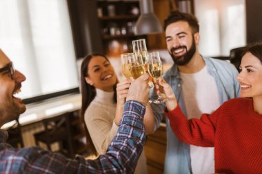 Gençler şampanya kadehleriyle tezahürat yapıyor ve ev partisi yaparken mutlu görünüyorlar..