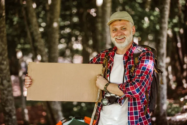 Usmívající Vousatý Muž Drží Prázdný List Papíru Venku Přírodním Pozadí — Stock fotografie