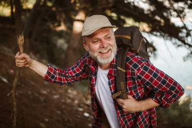 Olgun bir adam, deniz kenarında yürüyüş yapıyor ve gün batımında doğayı keşfediyor..