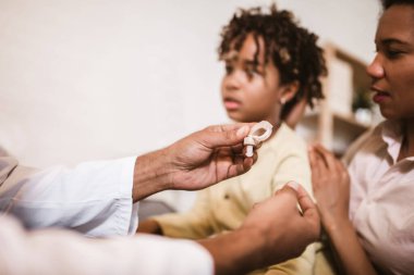 Doktorun muayenehanesinde kulağı takılı gülümseyen sağır Afrikalı Amerikalı kız..