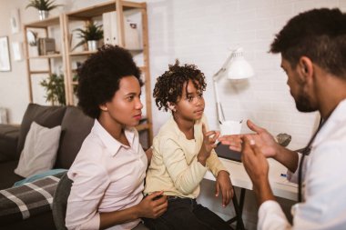Doktorun muayenehanesinde kulağı takılı gülümseyen sağır Afrikalı Amerikalı kız..