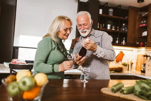 Senior couple in love in the kitchen and drinking wine.