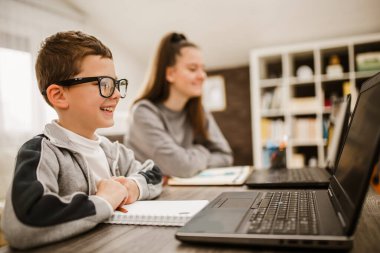 Oğlan ve kız evde çalışıyor ve okul ödevi yapıyor. Uzaklık öğrenimi çevrimiçi eğitim.