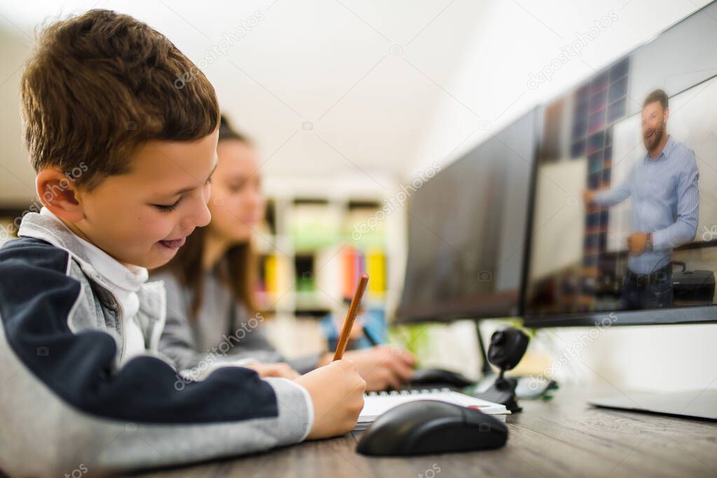 Boy and girl studies at home and doing school homework. Distance learning online education.