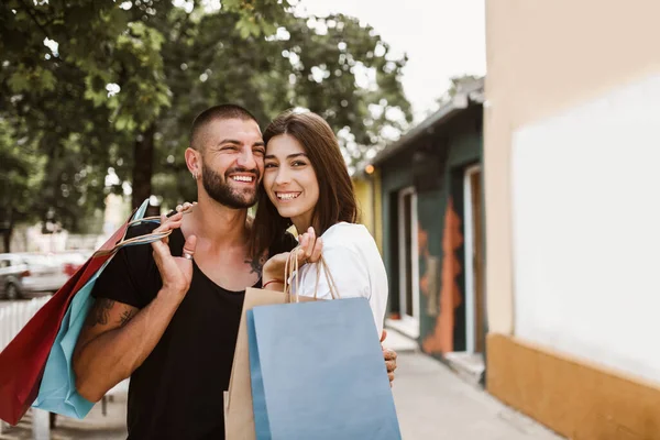 街で買い物をした後のショッピングバッグと幸せなカップルの肖像笑顔と抱擁 — ストック写真