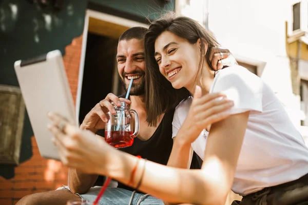 デジタルタブレットを使って夫婦を抱きかかえ 笑顔でカフェで話す — ストック写真