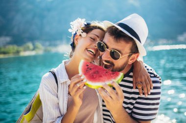 Kumsalda karpuz yiyen genç çift eğleniyor.