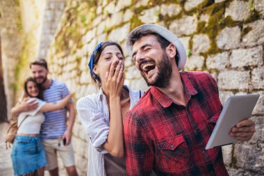 Mutlu arkadaşlar şehri gezmekten zevk alıyorlar, eğleniyorlar, dijital tablet kullanıyorlar..