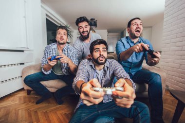 Gülümseyen erkek arkadaşlar evde oyun oynuyorlar ve eğleniyorlar..