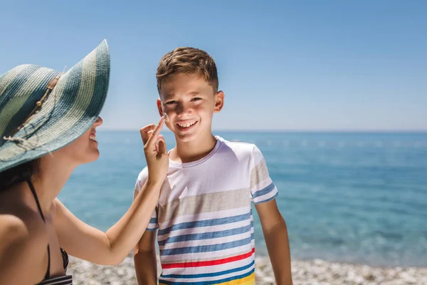 Woman hand putting sun lotion on child face.