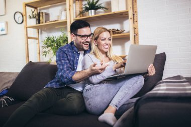 Mutlu çift evde dizüstü bilgisayar kullanırken iletişim kuruyor..