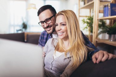 Mutlu çift evde dizüstü bilgisayar kullanırken iletişim kuruyor..