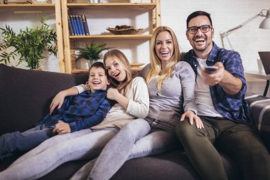 Mutlu bir aile evde televizyon izleyip birlikte eğleniyor..