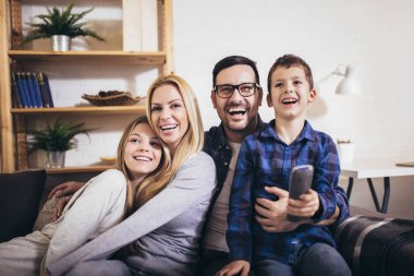 Mutlu bir aile evde televizyon izleyip birlikte eğleniyor..
