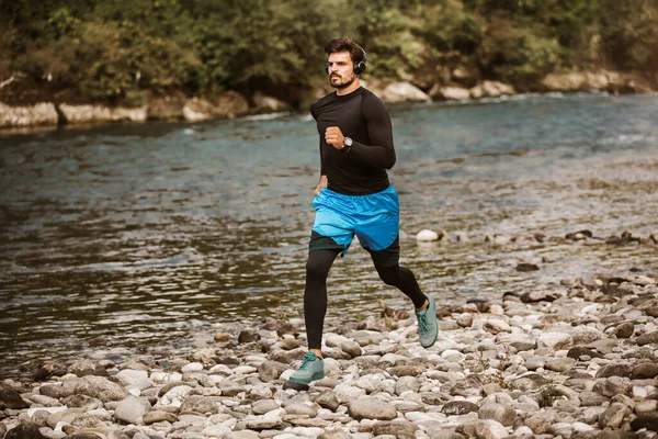 Young male athlete having a morning jogging next to the river.