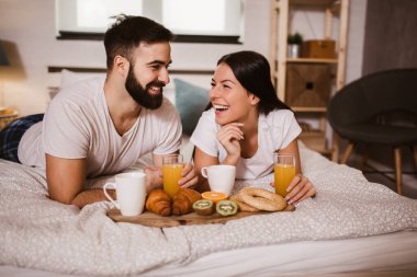 Yatak odasında kahvaltı yapan tatlı bir çift.