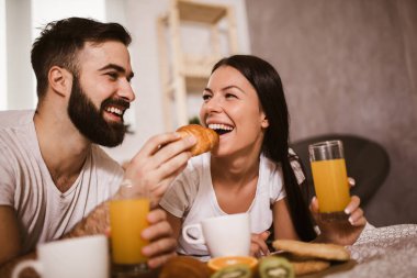Yatak odasında kahvaltı yapan tatlı bir çift.