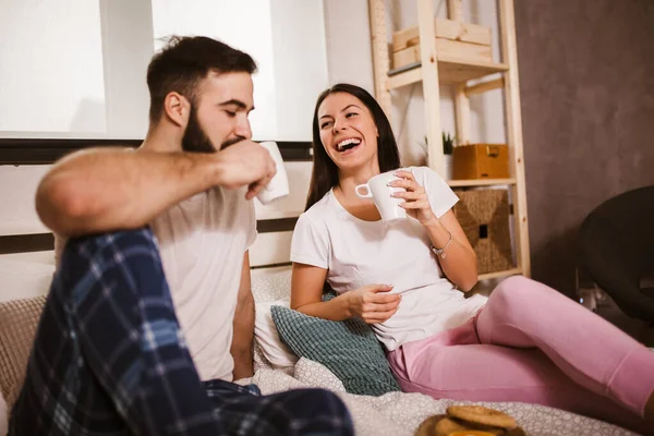 若いですカップルでベッドでコーヒーを飲み お互いを見て — ストック写真