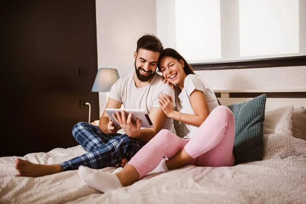Evde Yatakta Dijital Tablet Kullanan Gülümseyen Rahat Genç Çift — Stok fotoğraf