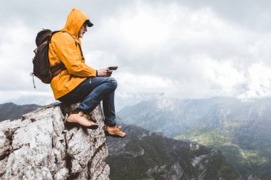 Orta yaşlı yağmurluk ve sırt çantalı gezgin dağların keyfini çıkarıyor..