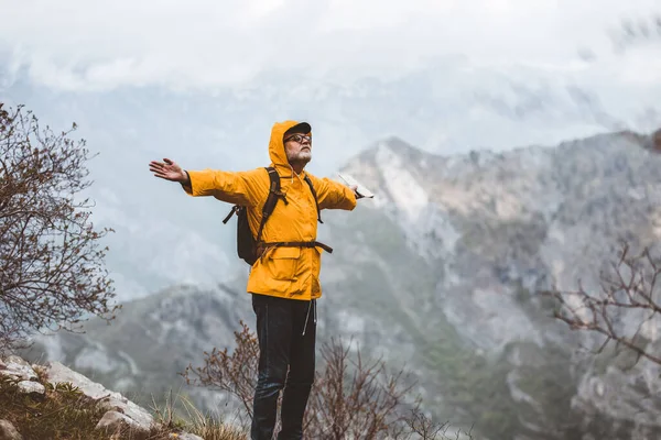レインコートとバックパックで山の景色を楽しむ中世の男性旅行者 — ストック写真