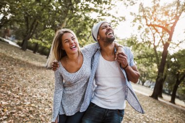 Parktaki romantik ve mutlu melez genç çiftin açık hava portresi.
