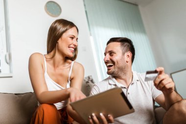 Mutlu genç çift tabletle online alışveriş yapıyor.