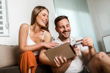Mutlu genç çift tabletle online alışveriş yapıyor.