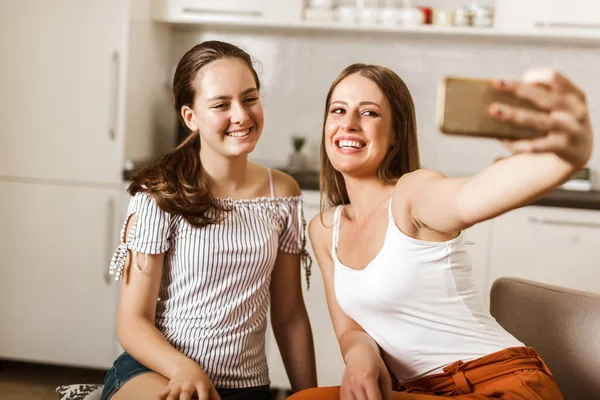 İki neşeli kız evde otururken selfie çekiyor.