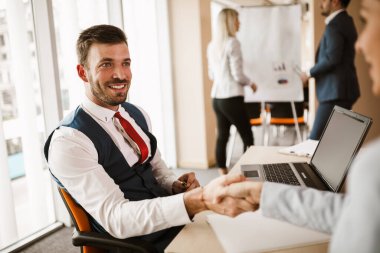 Yaratıcı ofiste çalışırken genç erkekler el sıkışıyor.