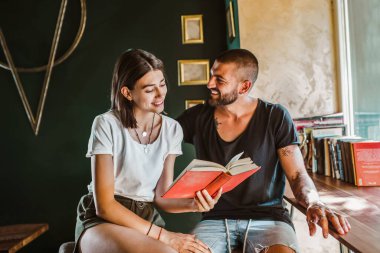 Kafede kitap okuyan genç bir çift.