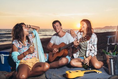 Mutlu arkadaşlar sahilde içkilerle parti yapıyorlar. Mutlu gençler plaj partisinde eğleniyor, birlikte kutluyorlar..