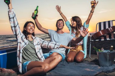 Mutlu arkadaşlar sahilde içkilerle parti yapıyorlar. Mutlu gençler plaj partisinde eğleniyor, birlikte kutluyorlar..