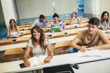 Konsantre öğrenciler üniversite konferans salonunda oturuyor.
