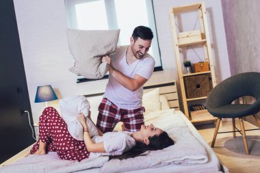 Yatak odasında yastıklarla kavga eden sevimli, genç bir çift..