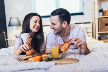 Yatak odasında kahvaltı yapan tatlı bir çift.